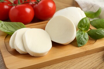 Tasty mozzarella, tomatoes and basil on wooden table, closeup