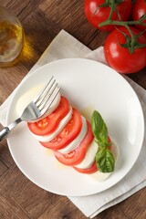 Tasty mozzarella, tomatoes, oil and basil on wooden table, flat lay
