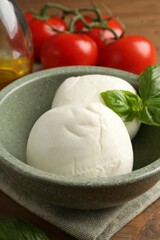 Tasty mozzarella balls, tomatoes and basil on wooden table, closeup