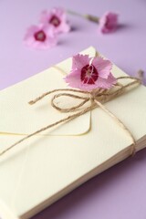 Stack of love letters and carnation flowers on violet background, closeup