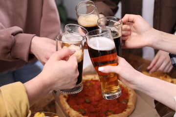 Friends clinking glasses of beer at table, closeup
