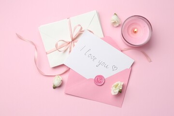 Stack of letters, card with phrase I Love You, burning candle and flowers on pink background, flat...