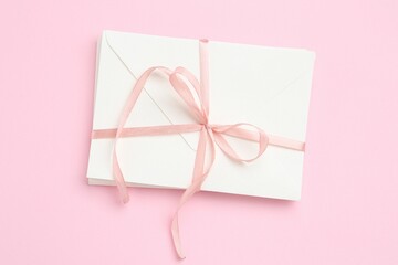 Stack of love letters on pink background, top view