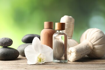 Composition with cosmetic products, spa stones and herbal bags on wooden table, closeup