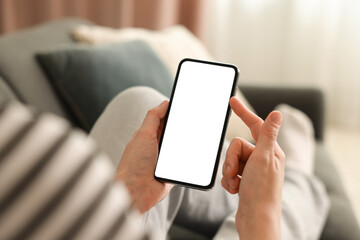 Woman using modern smartphone on sofa at home, closeup