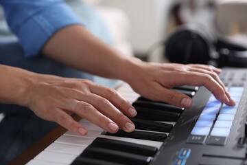 Woman working with MIDI keyboard indoors, closeup