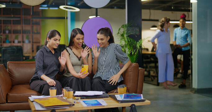 Indian young adult young adult woman lady hold mobile look cam talk gossip on video call at work place happy female girl staff use phone speak distant enjoy break spend time have fun joy job office