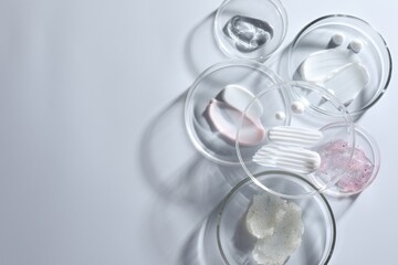 Different cosmetic products in Petri dishes on white background, flat lay. Space for text