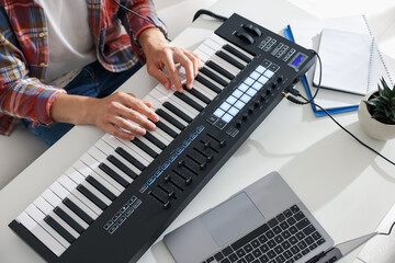 Man working with MIDI keyboard at white table indoors,