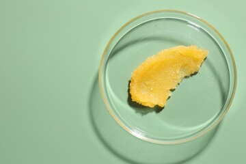 Cosmetic product in Petri dish on green background, top view. Space for text