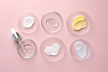 Different cosmetic products in Petri dishes and dropper on pink background, flat lay