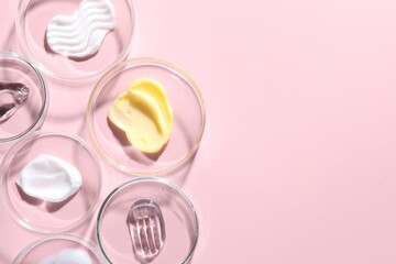 Different cosmetic products in Petri dishes on pink background, flat lay. Space for text