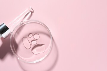 Cosmetic product in Petri dish and dropper on pink background, flat lay. Space for text