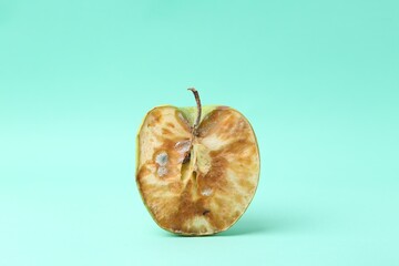 Half of spoiled apple on turquoise background