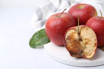 Spoiled apple and good ones on white table, closeup. Space for text