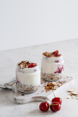 Healthy breakfast yogurt with multigrain granola, cherry,  and chocolate in glass jar