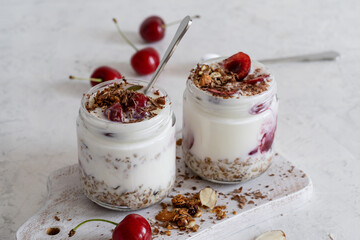 Healthy breakfast yogurt with multigrain granola, cherry,  and chocolate in glass jar