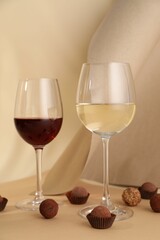 Delicious truffle bonbons and wine on beige background