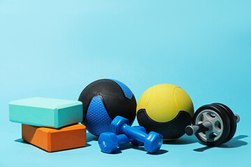 Medicine balls, foam blocks, ab wheel and dumbbells on light blue background