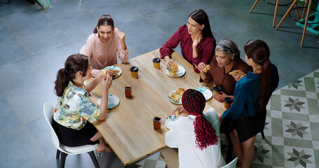 Indian happy woman staff sitting around table with old aged lady talk gossip eat tasty pizza junk food enjoy break time female girl group team speak funny joke drink coffee have fun joy at work place