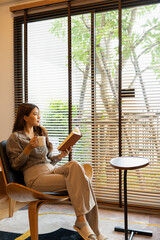 Woman enjoys book and music in modern abode.