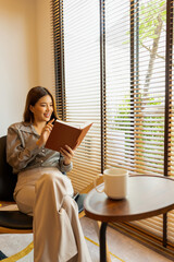 Woman enjoys book and music in modern abode.