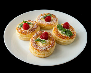 Close-up of puff pastry dessert with raspberries, whipped cream and mint on black background