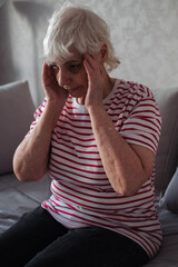 Old Age, Health Problem, Vision and People Concept - Close Up of Senior Woman Sitting on Sofa and Having Headache at Home. Elderly Woman With A Migraine