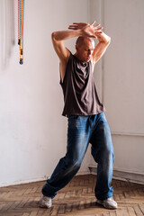 A forty year old sporty man in casual clothes dances in a room.