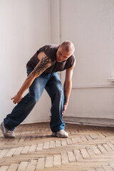 A sporty man in jeans dances a modern dance.