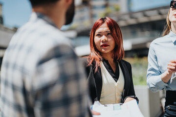 Group of business associates discussing work during urban meeting under sunny weather.