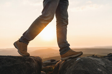 Hiker navigating rocky terrain with sunset backdrop in a scenic outdoor landscape showcasing...