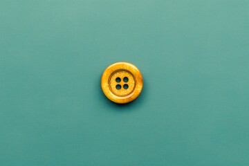 golden sewing button on teal fabric with elegant handcrafted texture