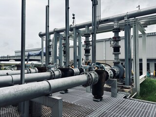  Industrial electric motor pumps installed outdoors with connected pipelines and valves, used in cooling systems, HVAC, and fluid transfer operations in factories or energy plants.