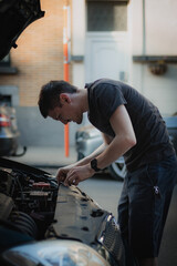 A young man removes the protective partition in the hood of a car.