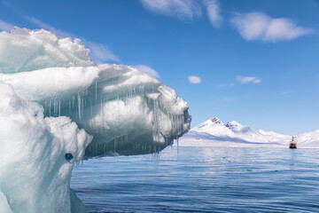 Iceberg with Icebreaker at anchor in the arctic waters of Svalbard, a Norwegian archipelago between...