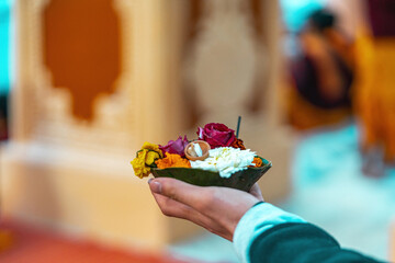 A traditional Indian flower offering altar held by a hand. Vibrant marigolds and petals used in Hindu rituals and prayers.