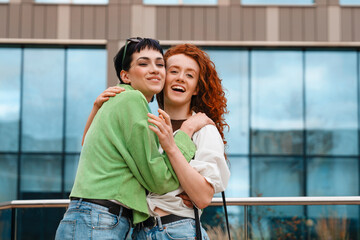 Two friends enjoy a joyful moment together outdoors in a modern urban setting during a sunny day