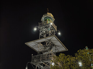 The unique, modern minaret of Masjid Agung Demak, illuminated at night against a dark sky.