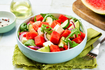 Fresh summer salad with watermelon, arugula, feta, cucumber salad, healthy food eating. Light background.