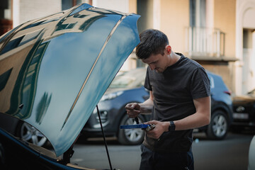 A young man holds tools for auto repair.