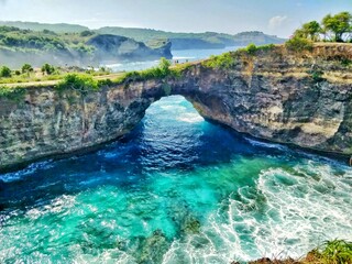 A beautiful natural rock arch over a turquoise sea or river.