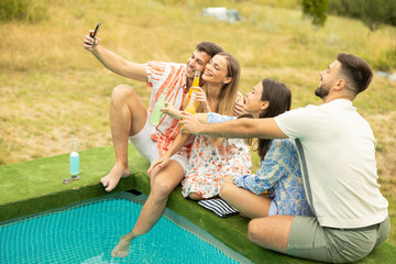 The group of friends poses for a selfie, capturing a joyful moment filled with laughter and drinks by the poolside.
