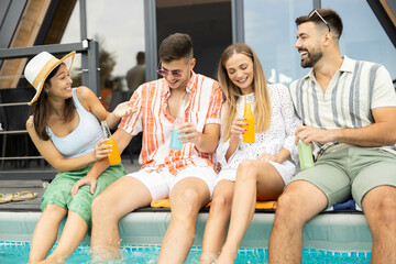 Friends raising their glasses in cheer by the pool, emphasizing friendship and joy during a vibrant summer day.