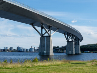 Modern highway bridge spanning over water near industrial area on a sunny day
