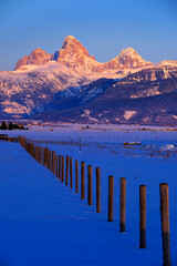 Teton Mountain Range in Winter at Sunset with Fence Leading Into the Horizon
