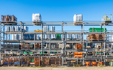 Bright and organized construction supplies stored on shelves under clear blue sky at a busy...