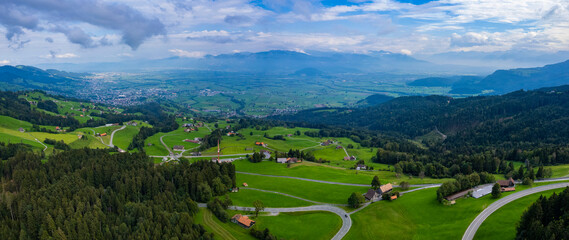 Aerial panoramic view of mountains and fields in Switzerland on a cloudy day in summer.