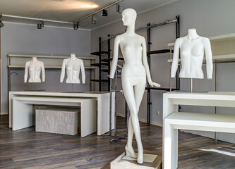 Display of white mannequins in a modern retail store showcasing fashion collections in a well-lit...