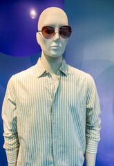 Trendy mannequin display featuring striped shirt and sunglasses in a retail store setting capturing...